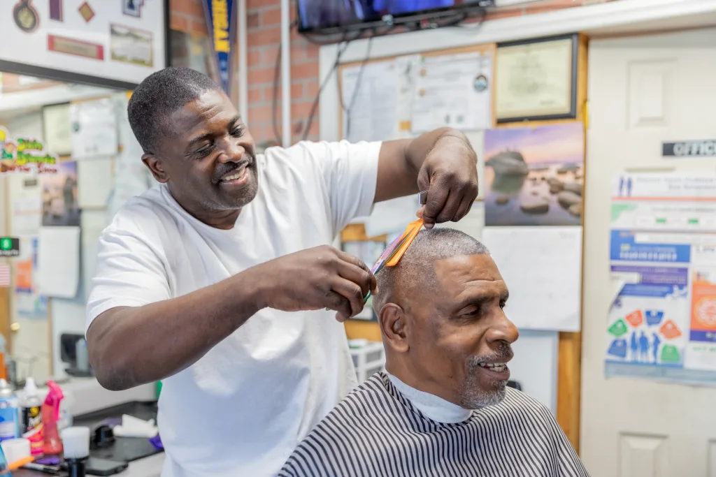 A man getting his hair cut by another man.